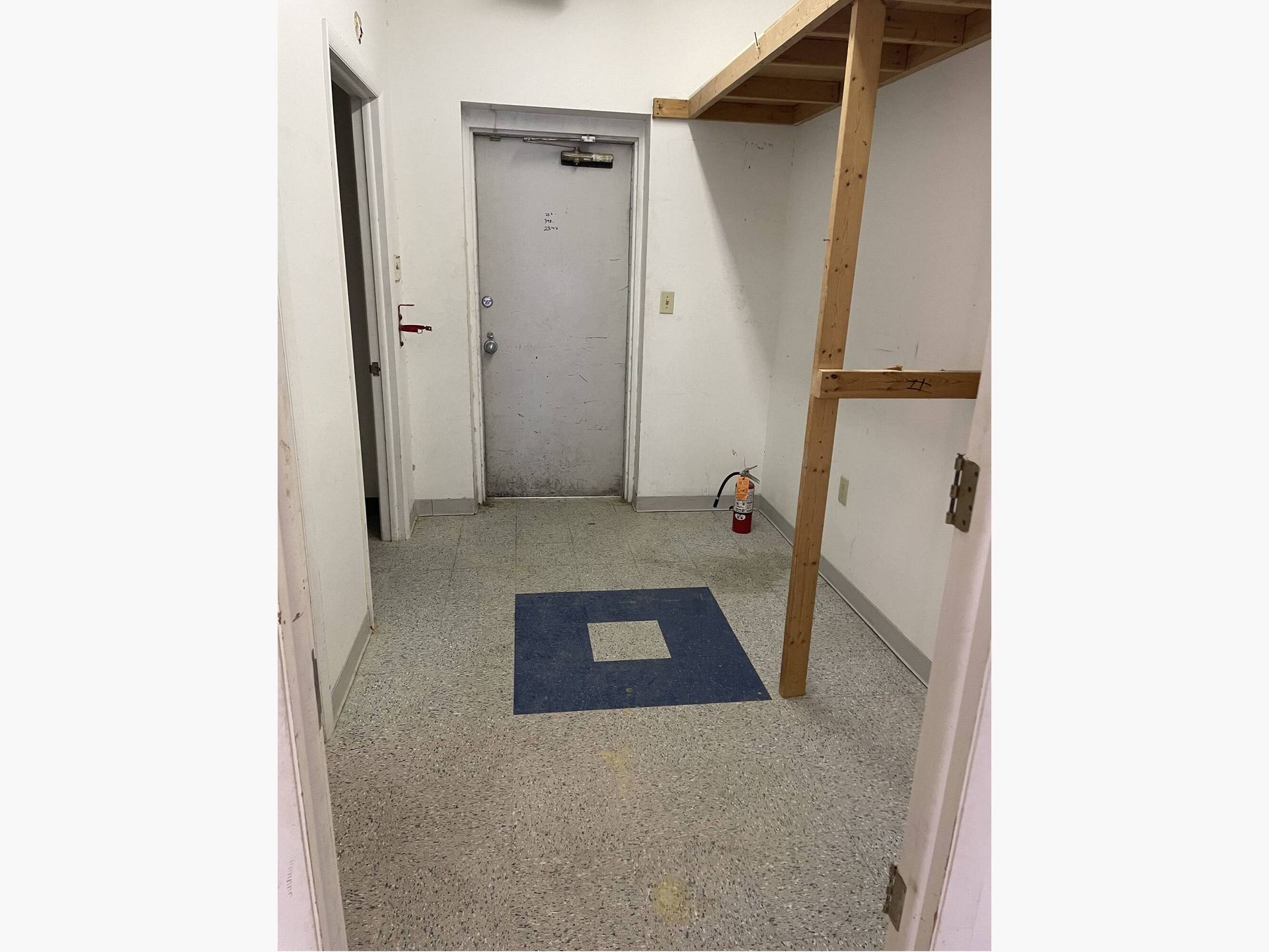 A hallway with a door and a blue square on the floor