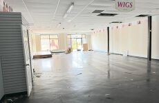 A large empty room with a sign that says wigs on the ceiling.