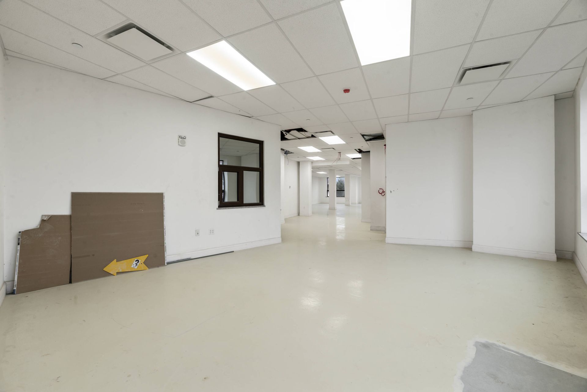An empty room with white walls and a yellow arrow pointing to the right.