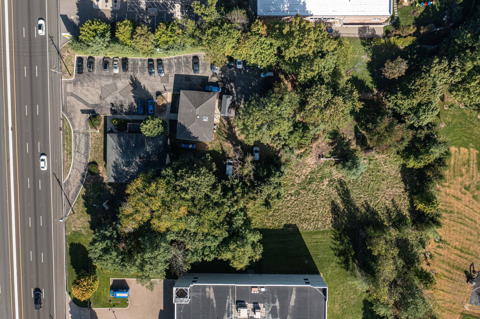 An aerial view of a house surrounded by trees and a highway.