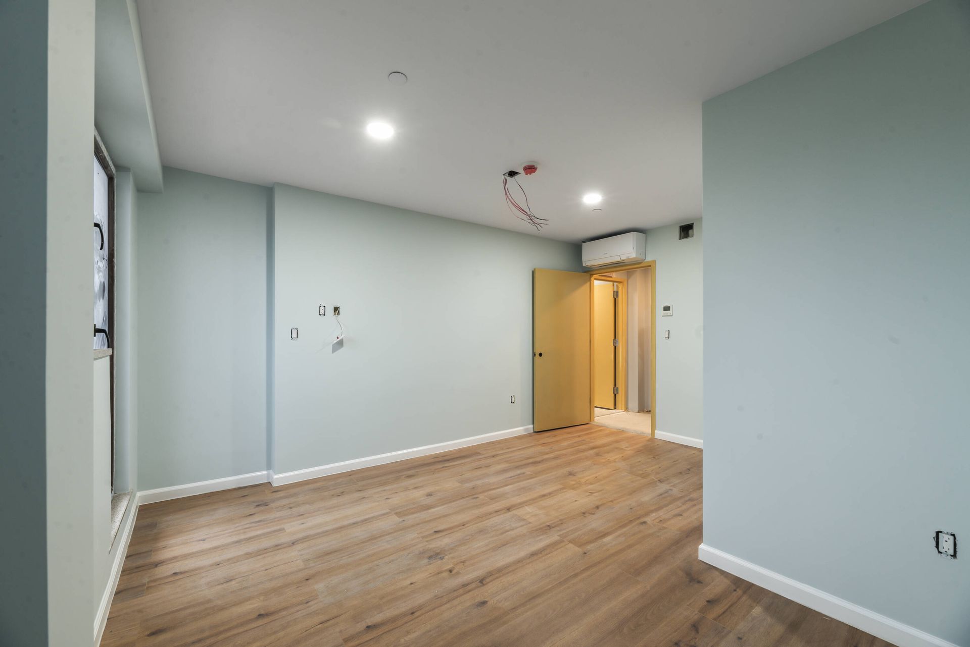 A large empty room with wooden floors and white walls.