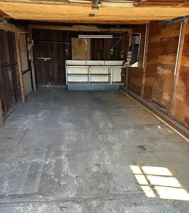An empty garage with a wooden wall and a concrete floor.