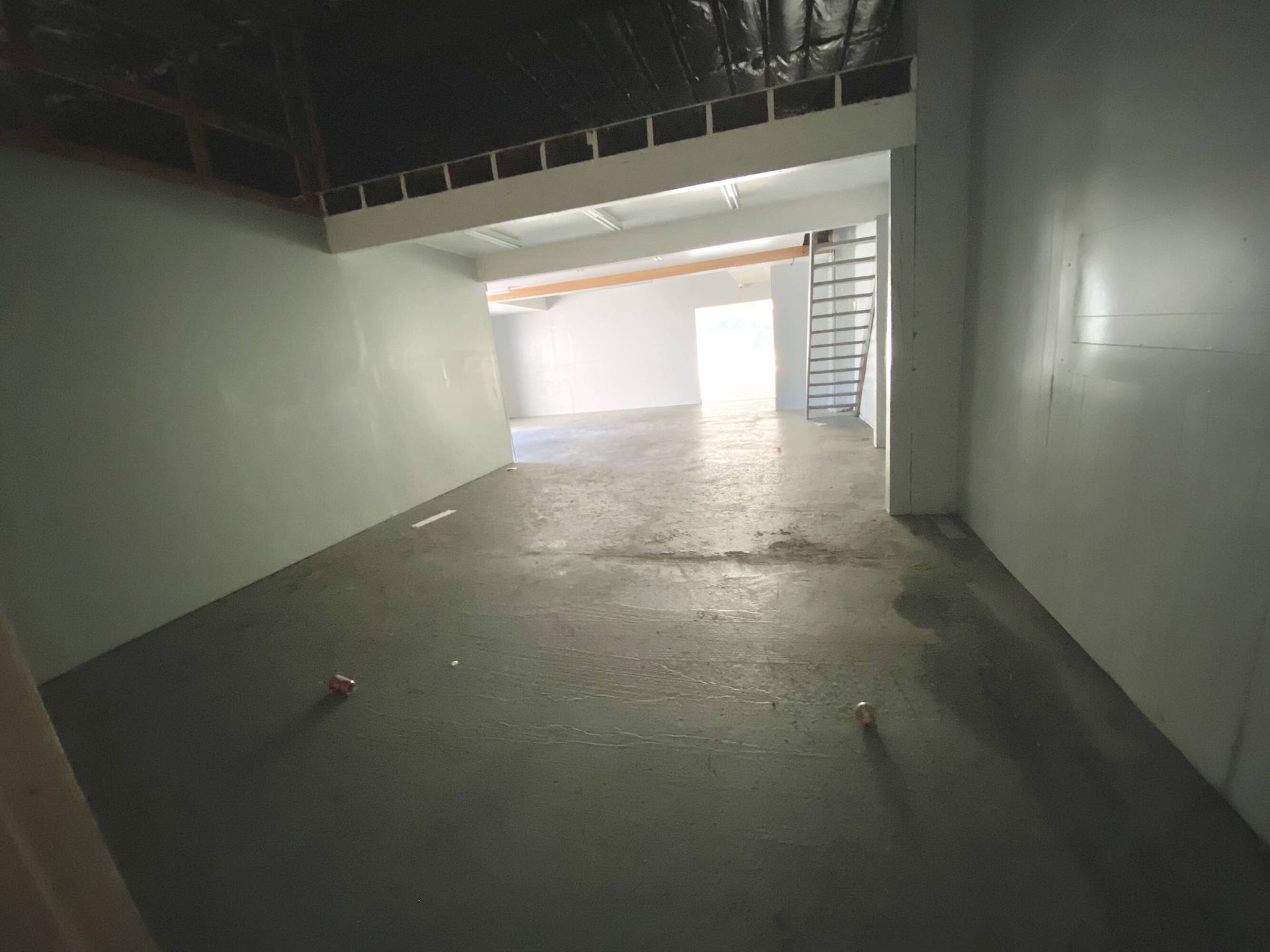 A large empty room with a staircase going up to the second floor.