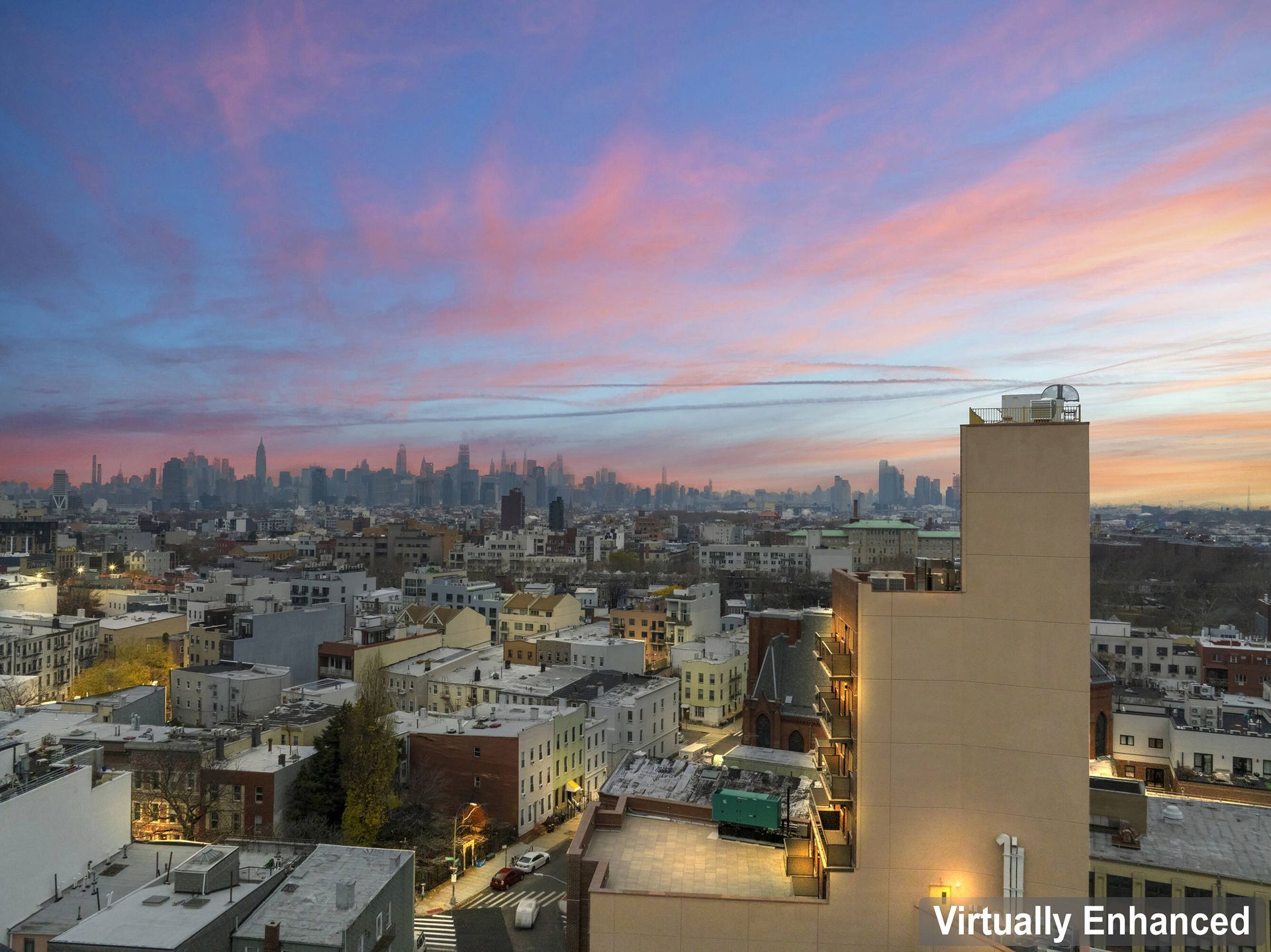 An aerial view of a city at sunset with a building in the foreground.