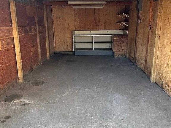 An empty garage with wooden walls and a concrete floor.