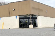 A large brown and white building with a car parked in front of it.
