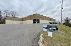 A large building with a for sale / lease sign in front of it.