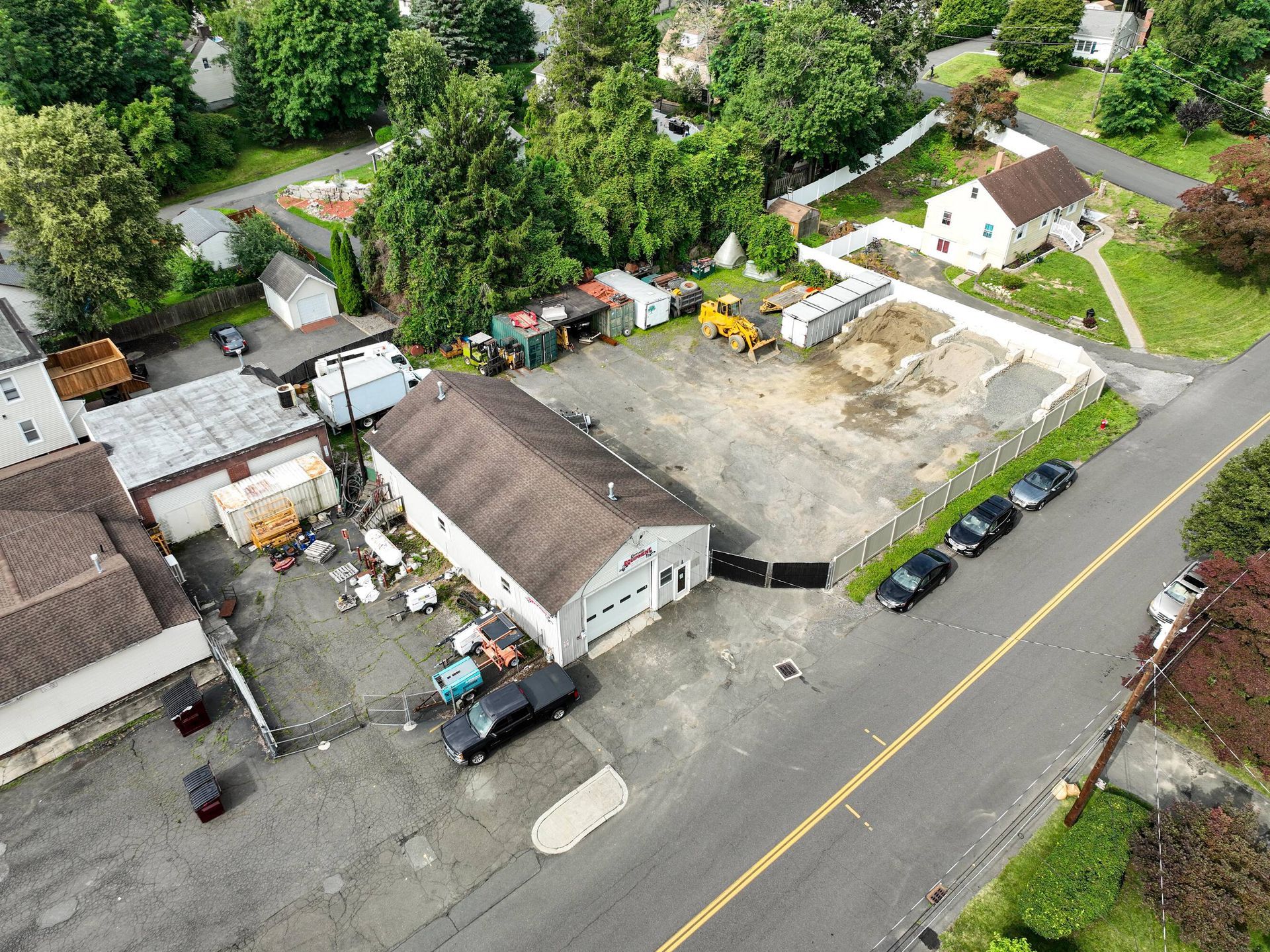 An aerial view of a residential area with a lot of buildings and cars parked on the side of the road.