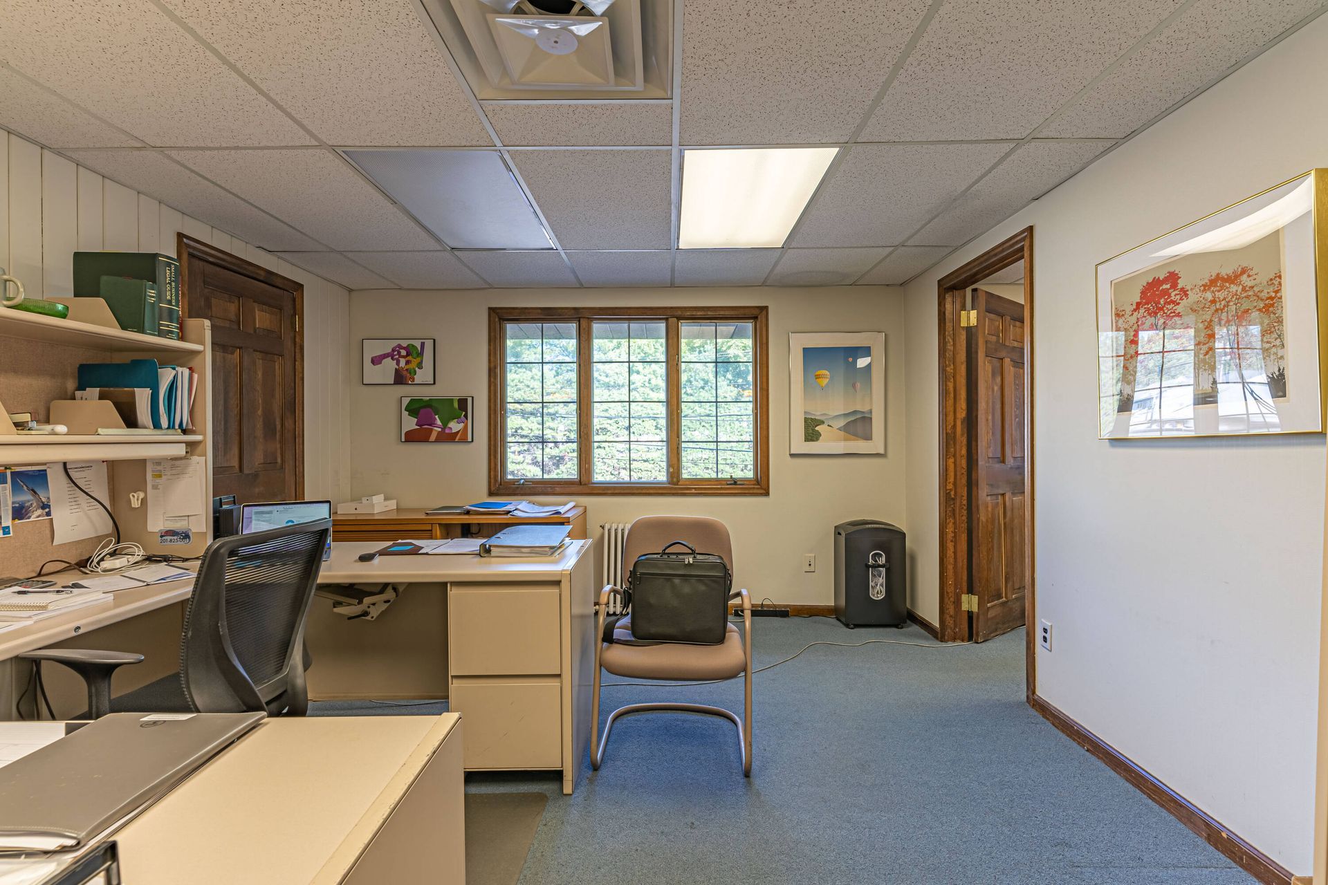 An office with a desk , chair , and a trash can.