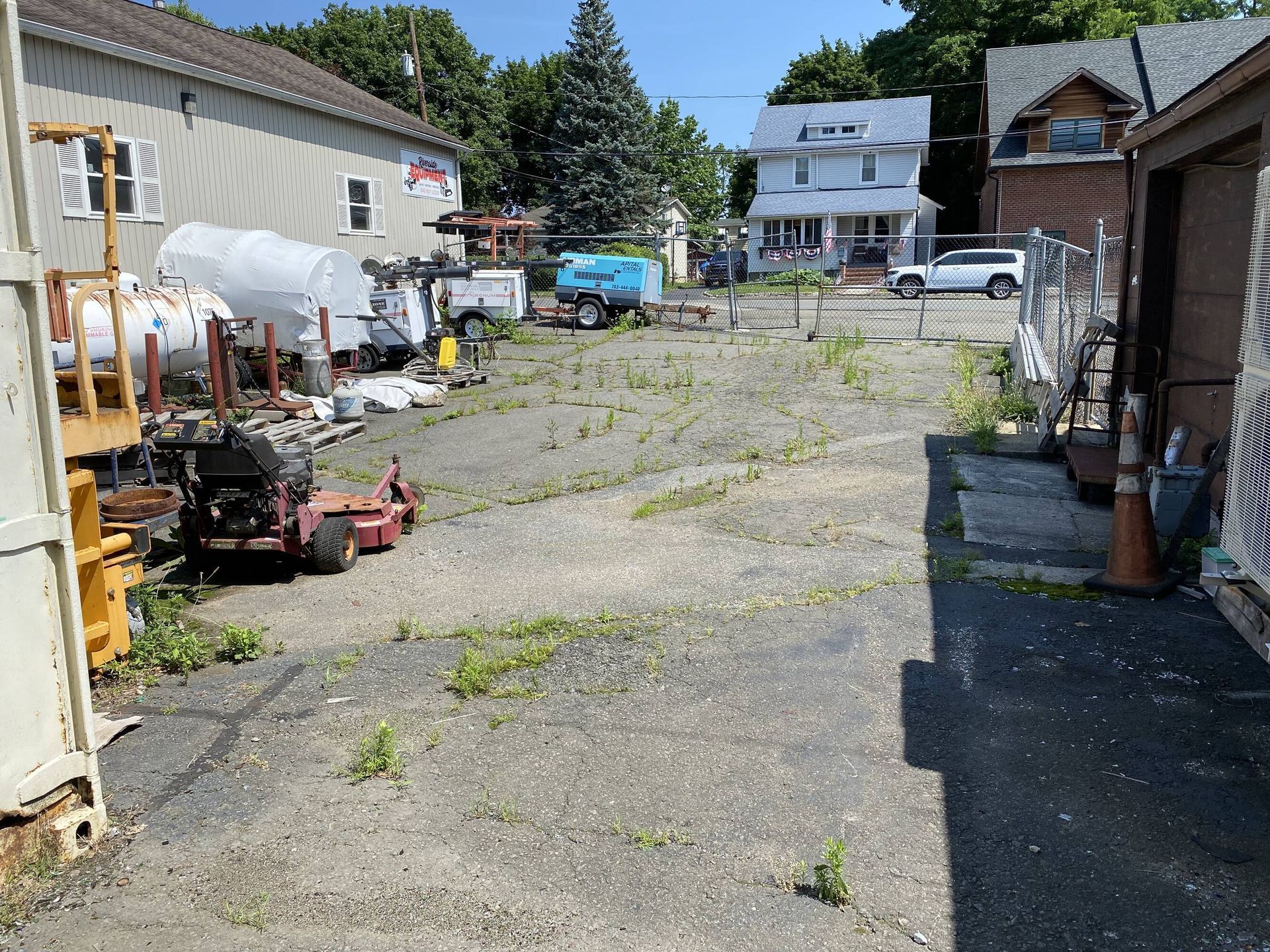 An empty lot with a lot of junk in it and a house in the background.