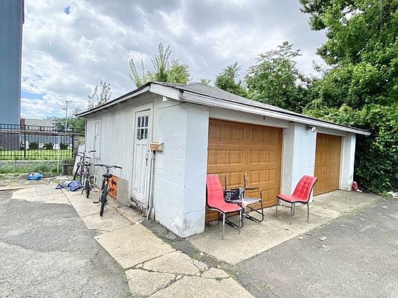 A white garage with a red chair and table in front of it.