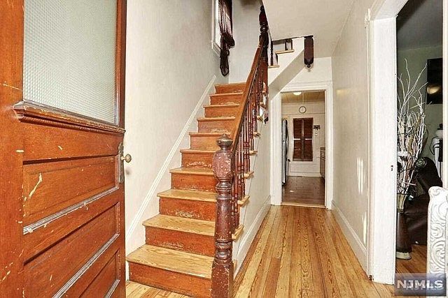 A hallway with stairs and a door that says njmls