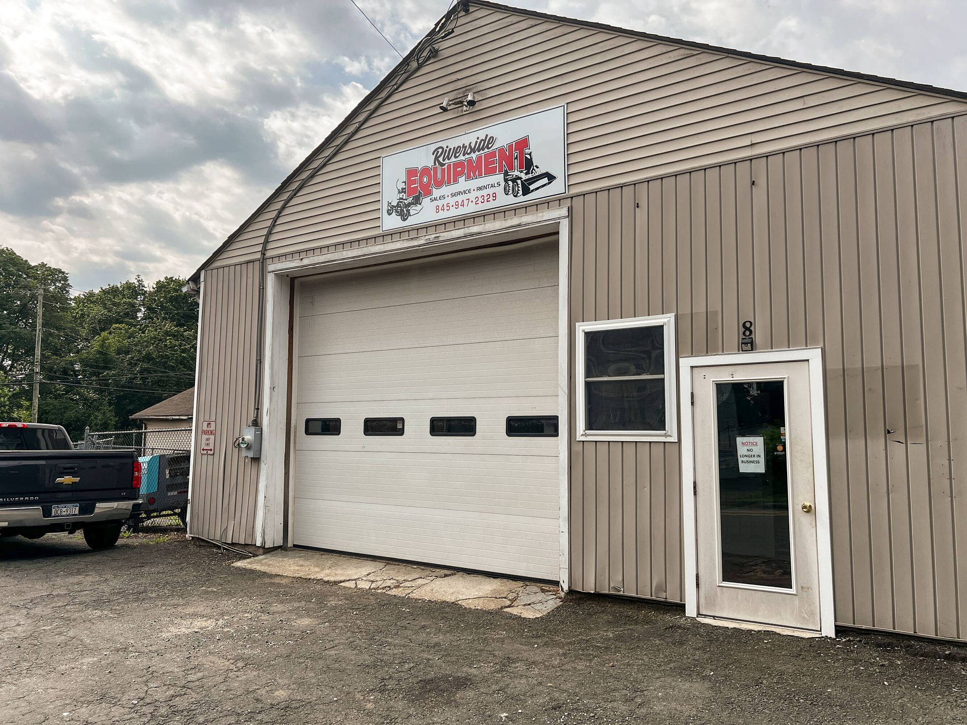 A truck is parked in front of a building with a large garage door.