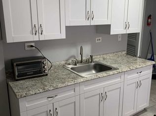 A kitchen with white cabinets , a sink , and a toaster oven.