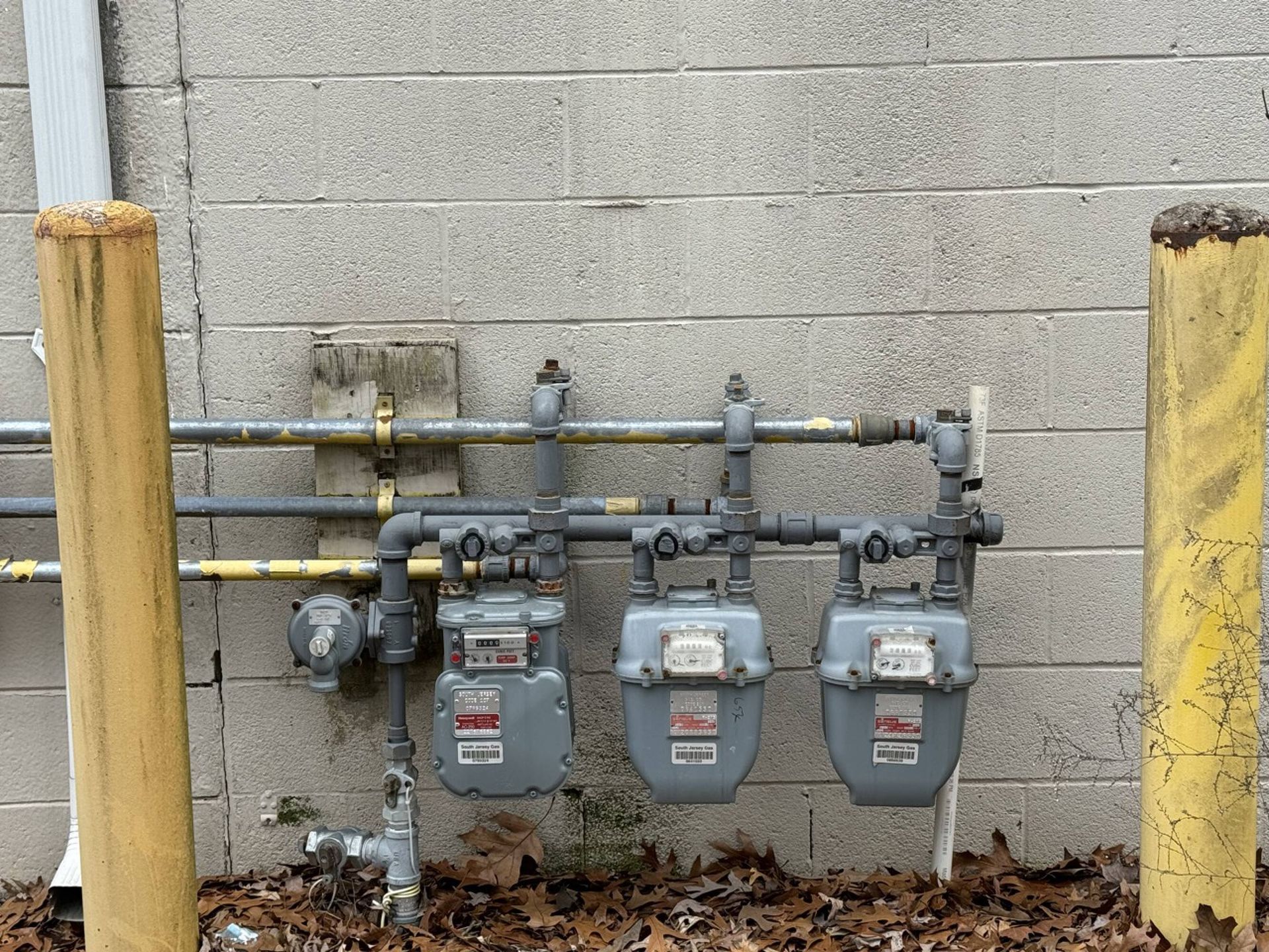 Three gas meters are attached to a brick wall