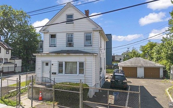 A white house with a fence around it and a car parked in front of it.