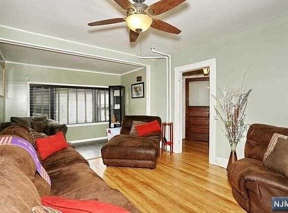 A living room with brown furniture and a ceiling fan
