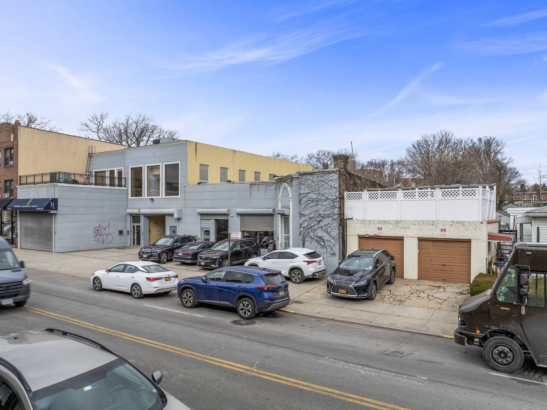 A row of cars are parked on the side of the road in front of a building.