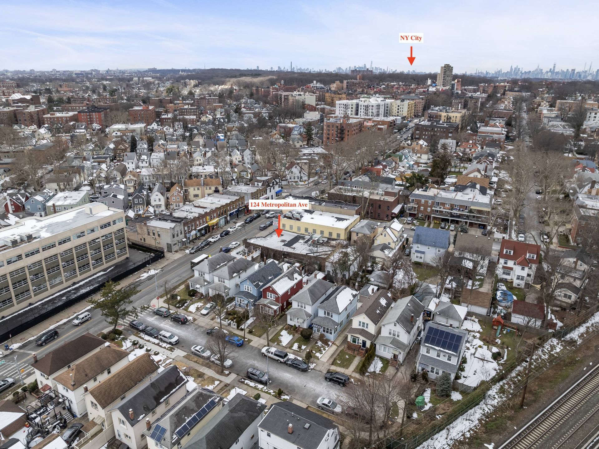 An aerial view of a city with a red arrow pointing to a building.