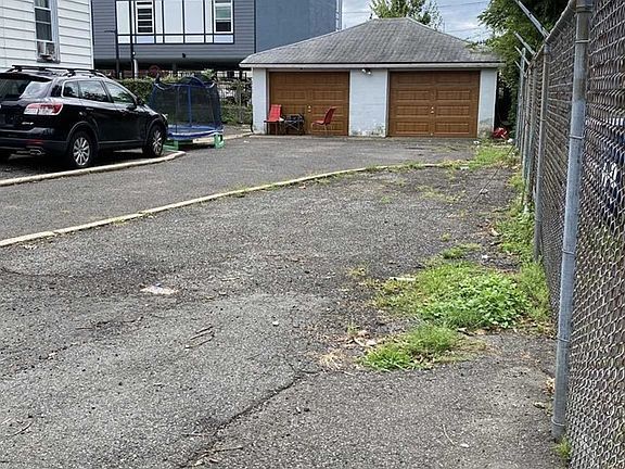 A car is parked in a parking lot next to a garage.