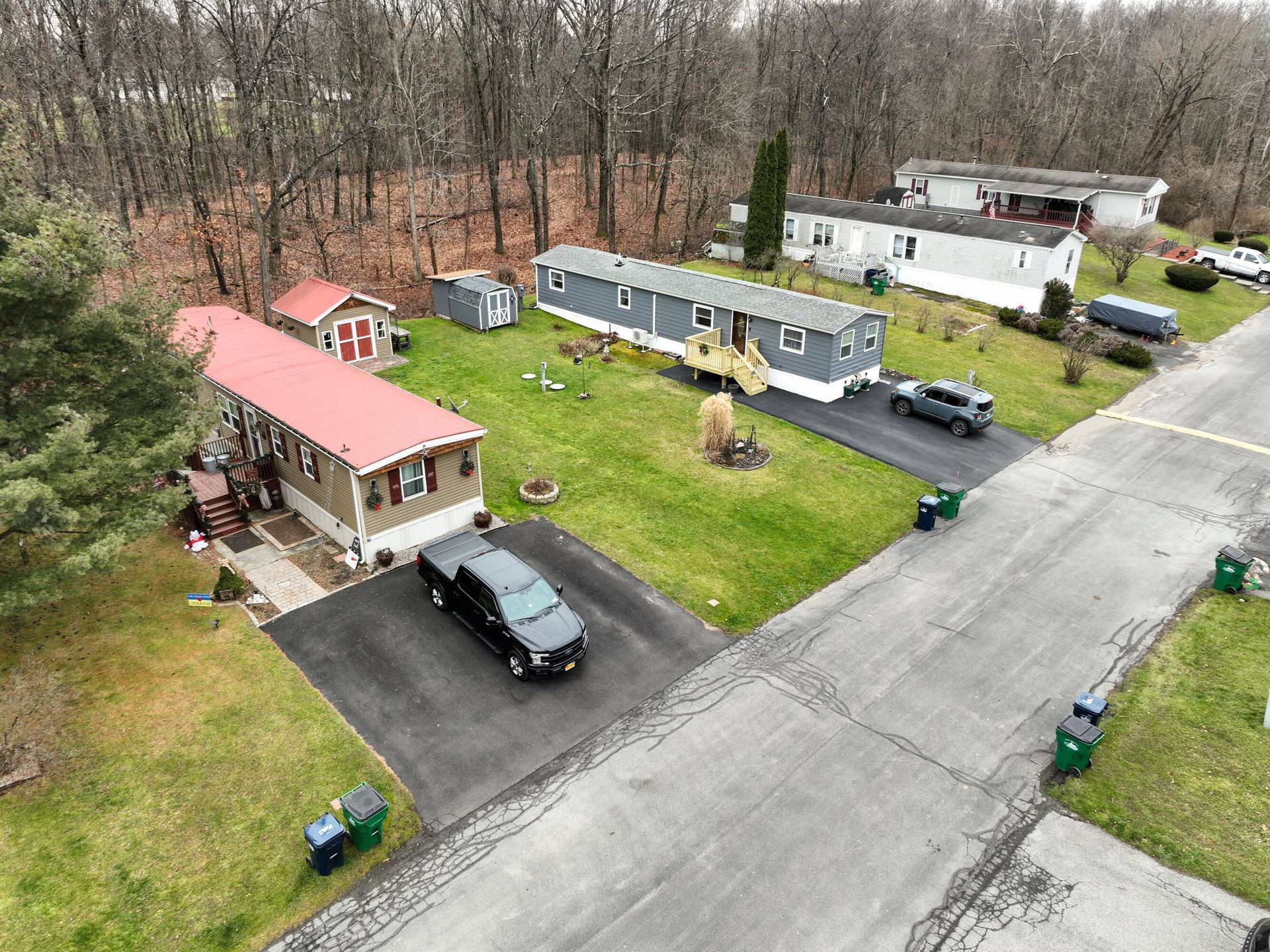 An aerial view of a mobile home park with a car parked in the driveway.