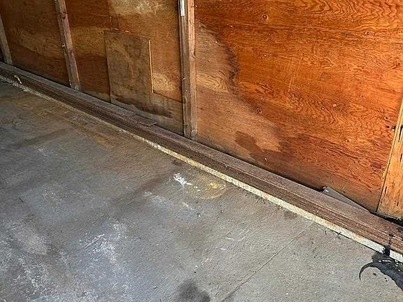 A wooden wall with a concrete floor in a garage.