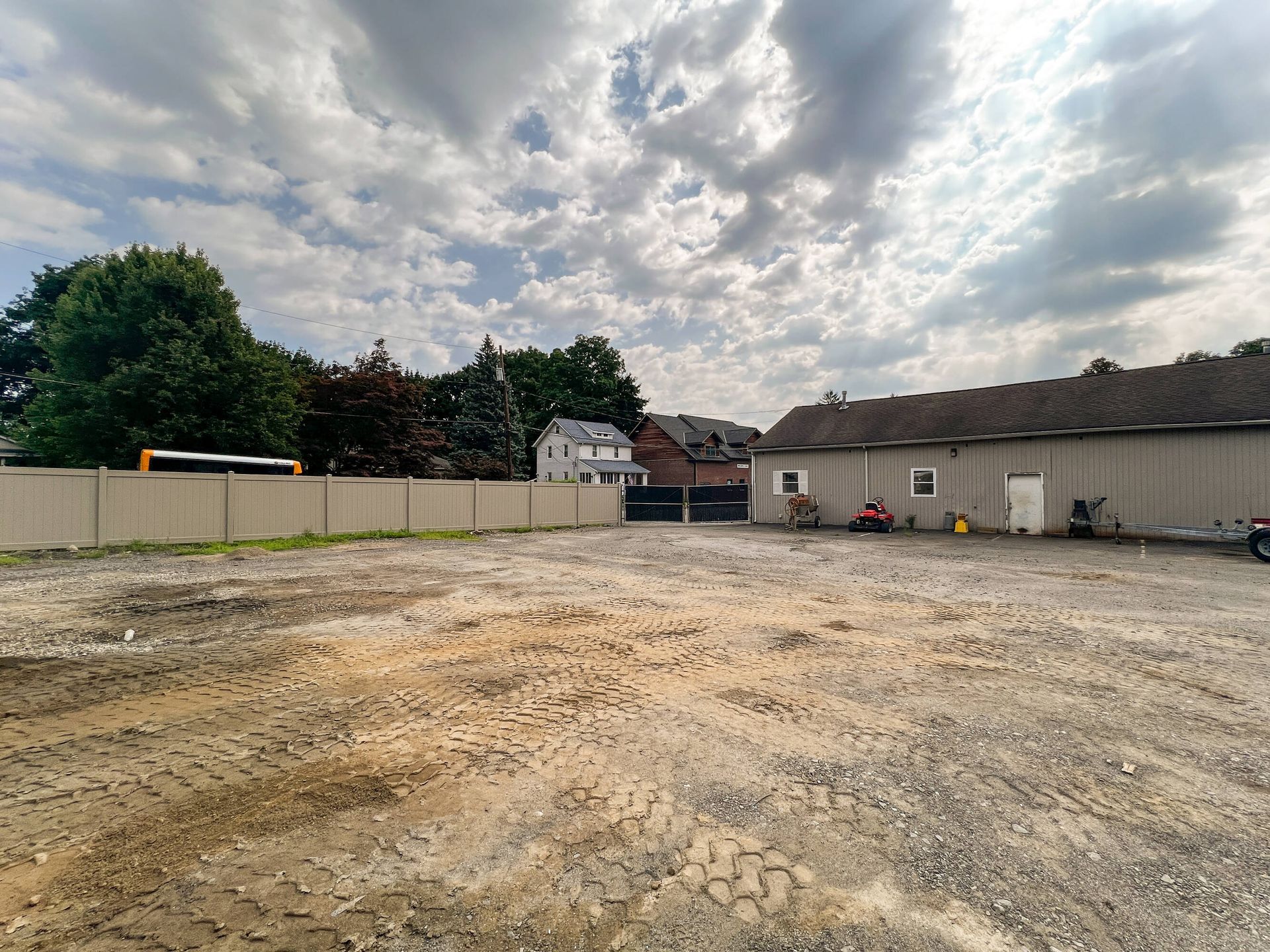 An empty lot with a fence and a building in the background