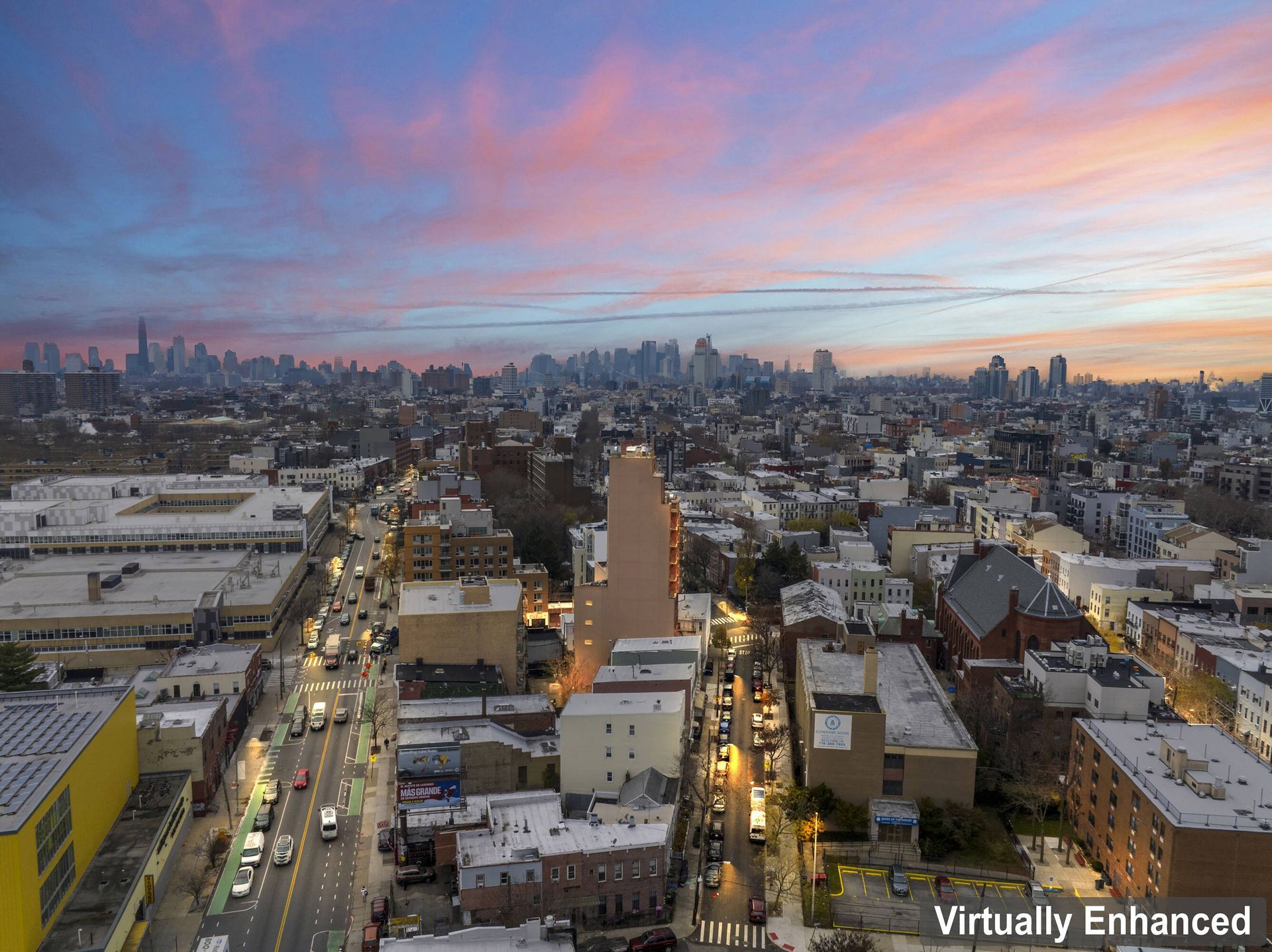 An aerial view of a city at sunset with a skyline in the background.