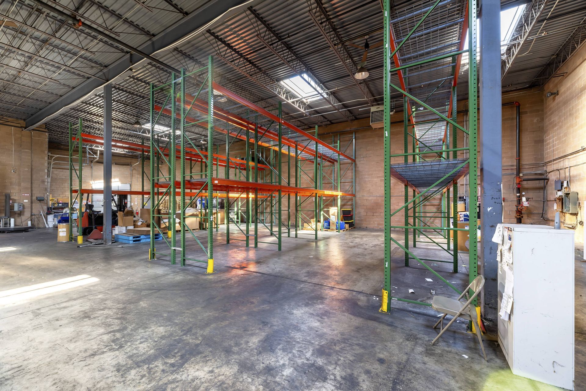 A large warehouse with lots of shelves and a skylight.