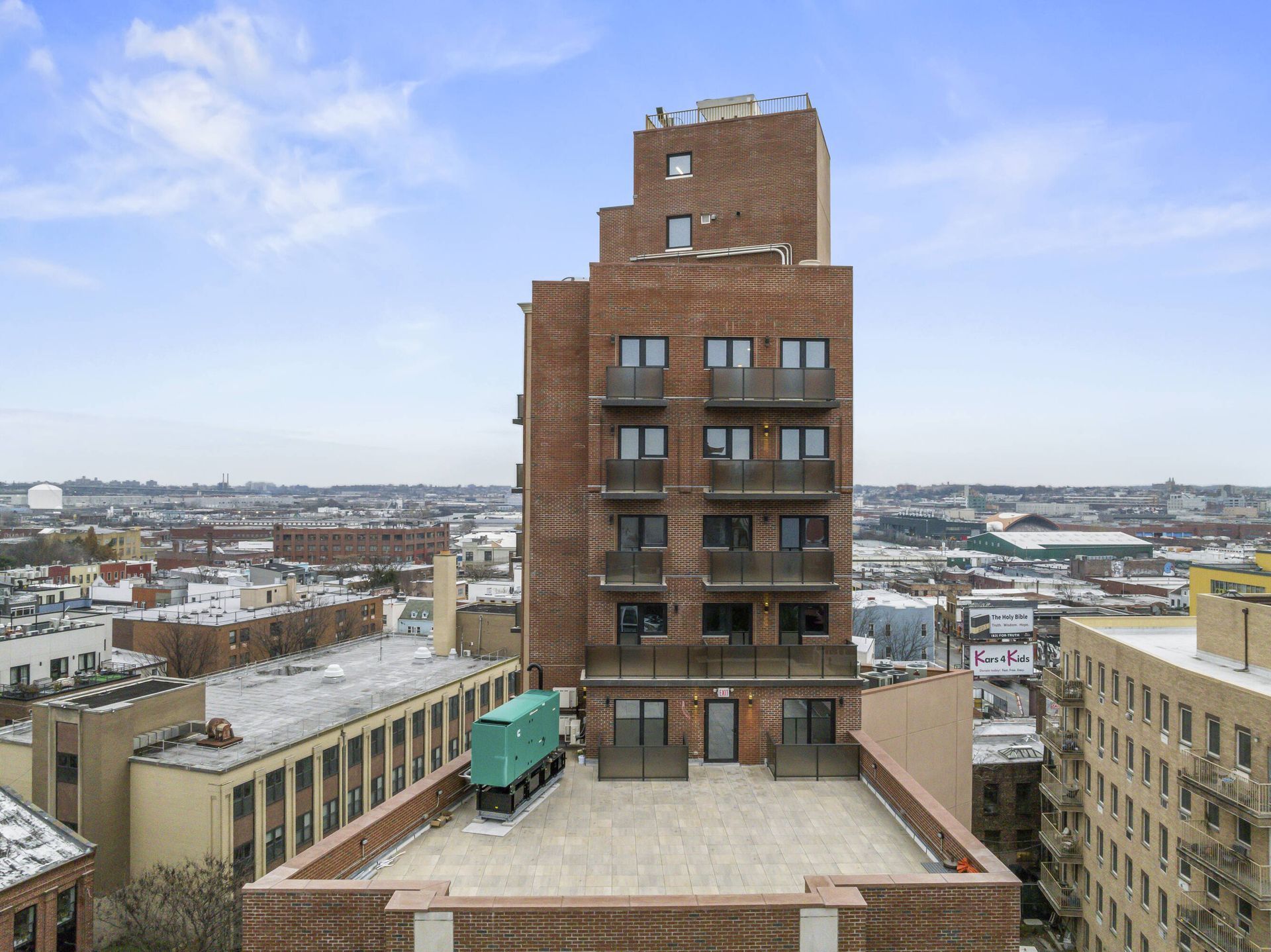 An aerial view of a brick building with a green truck parked on the roof