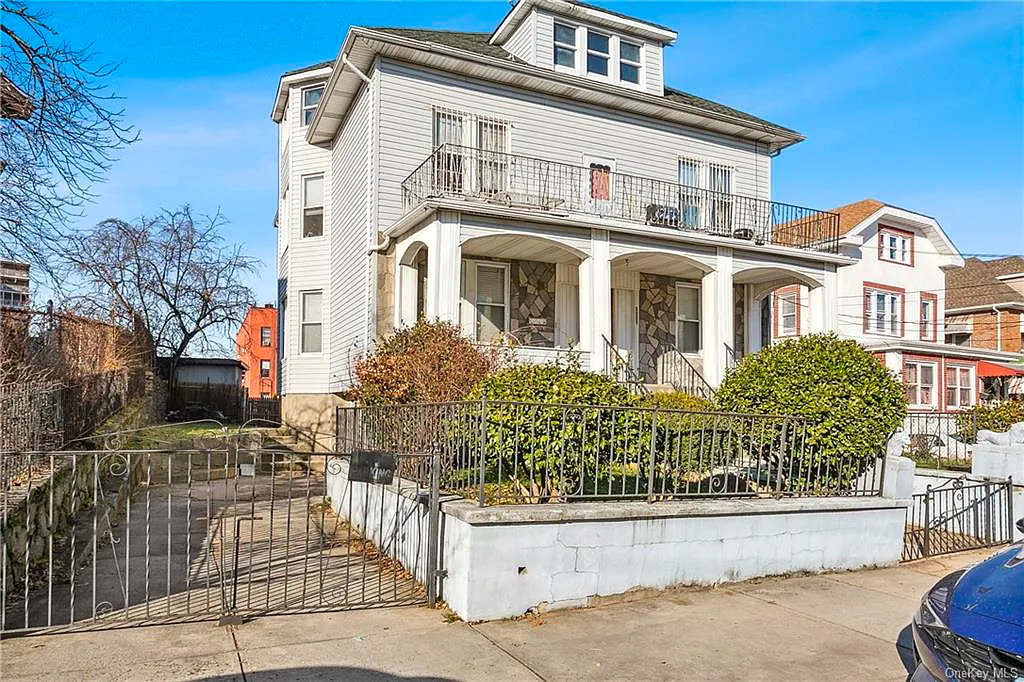 A large white house with a blue car parked in front of it.