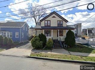 A house with a porch and stairs is sitting on the side of a street next to a blue house.