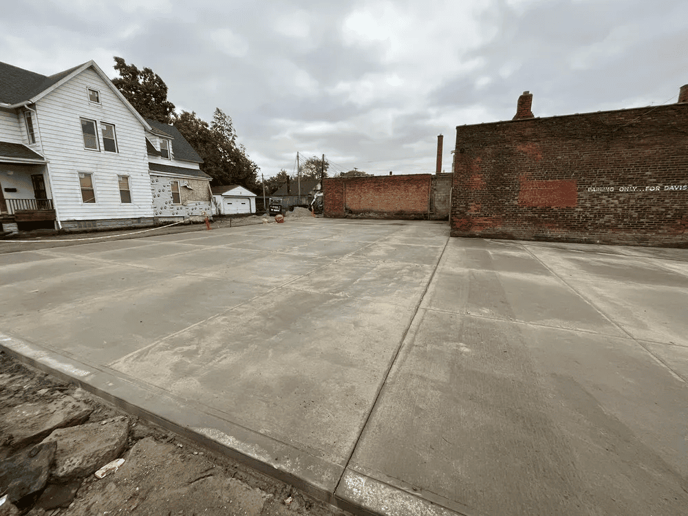 A concrete parking lot with a brick building in the background.