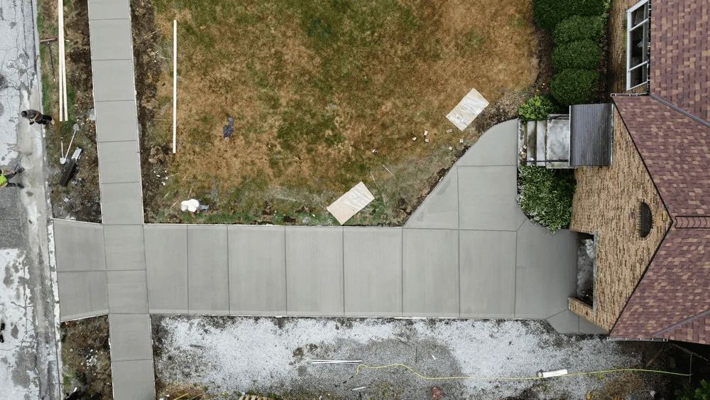 An aerial view of a concrete walkway leading to a house.
