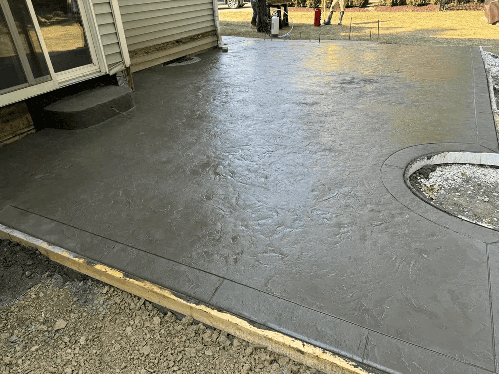 A concrete patio with a fire pit in the middle of it.