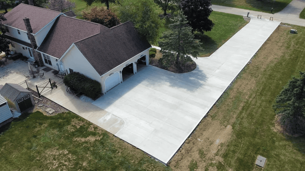 An aerial view of a house with a concrete driveway leading to it.