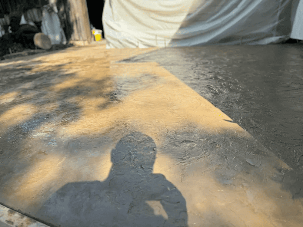 A shadow of a person is cast on a concrete surface.