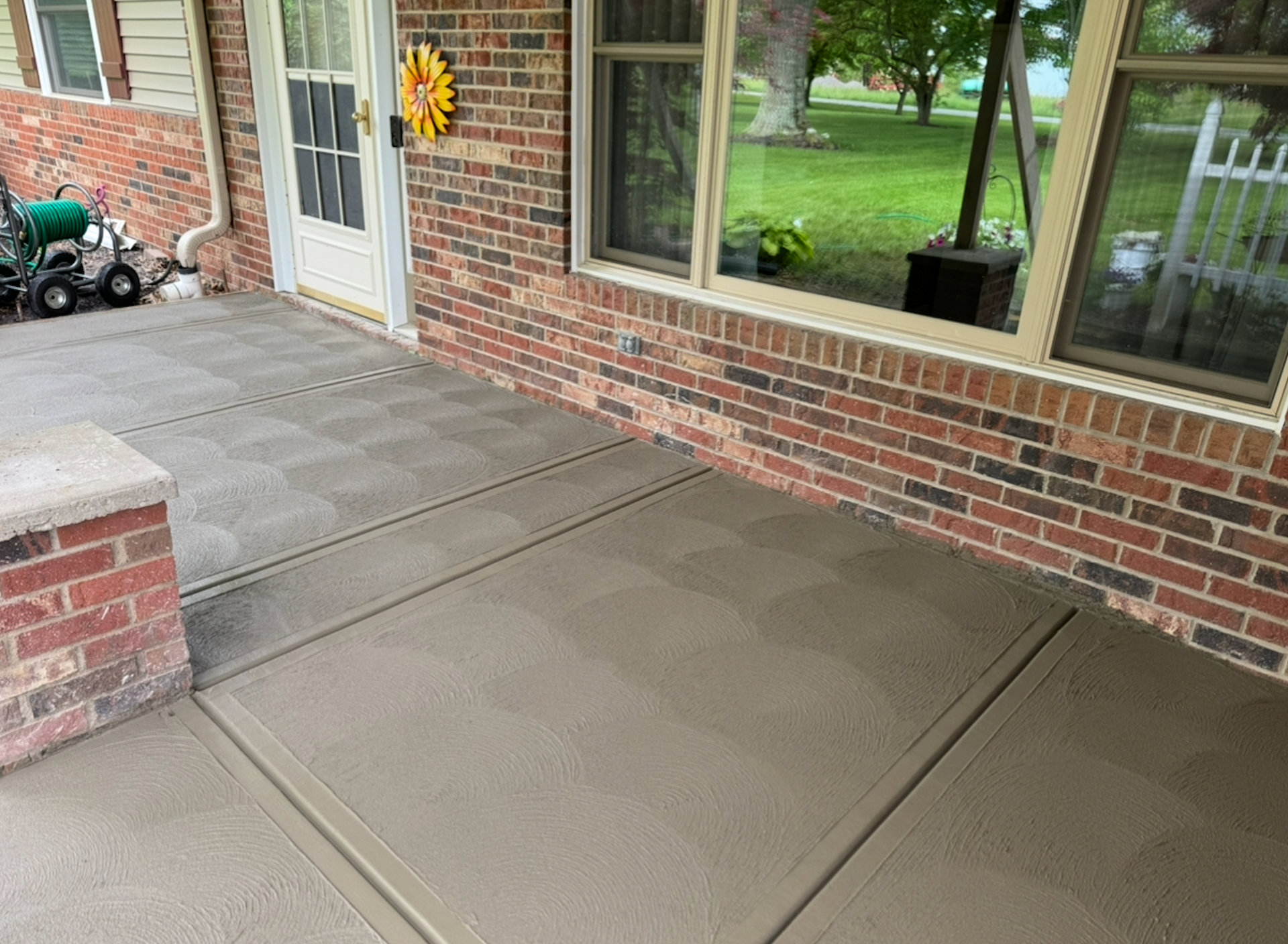 A brick house with a concrete porch and a toy tractor in front of it.