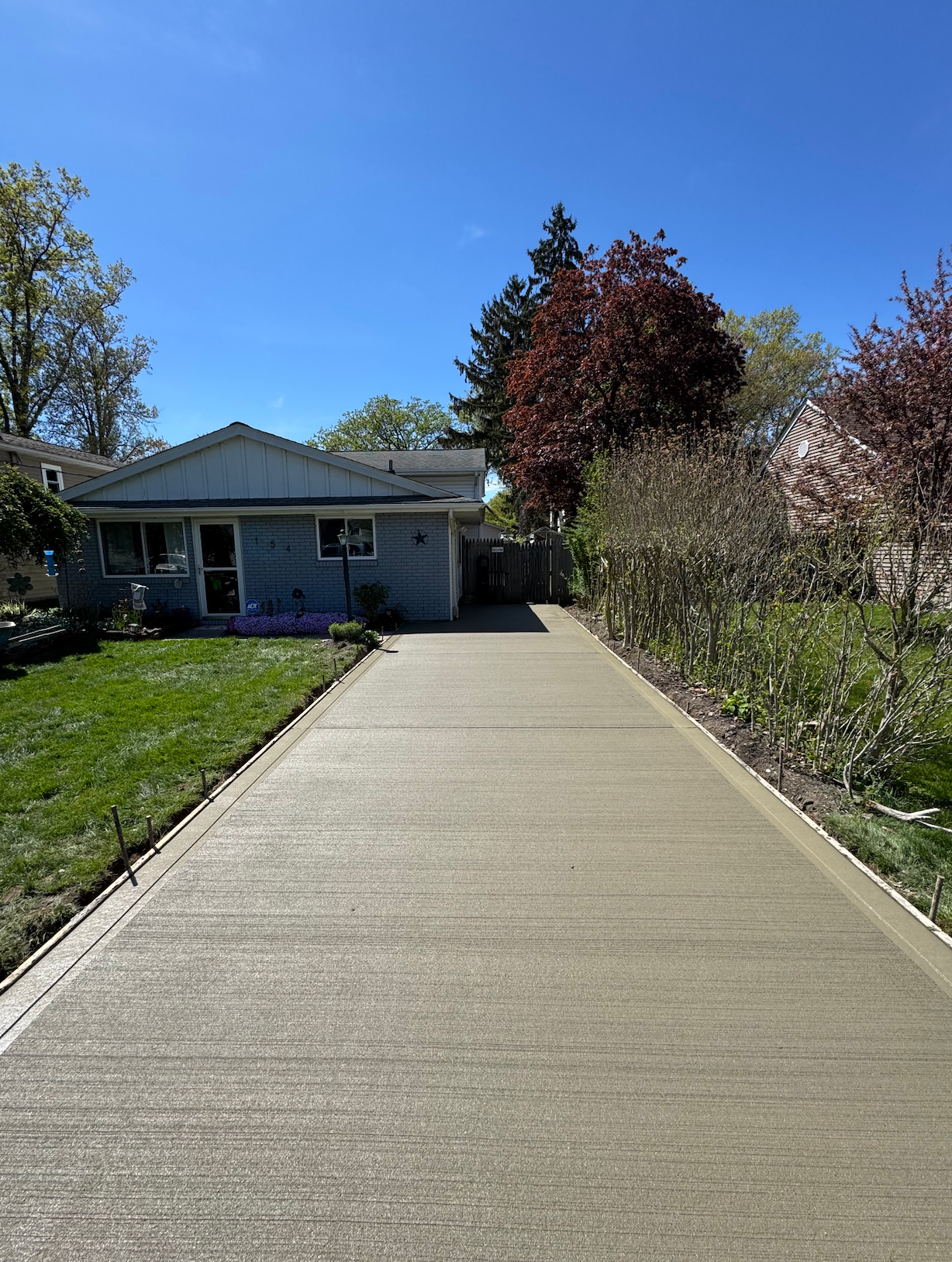 A concrete driveway leading to a house on a sunny day
