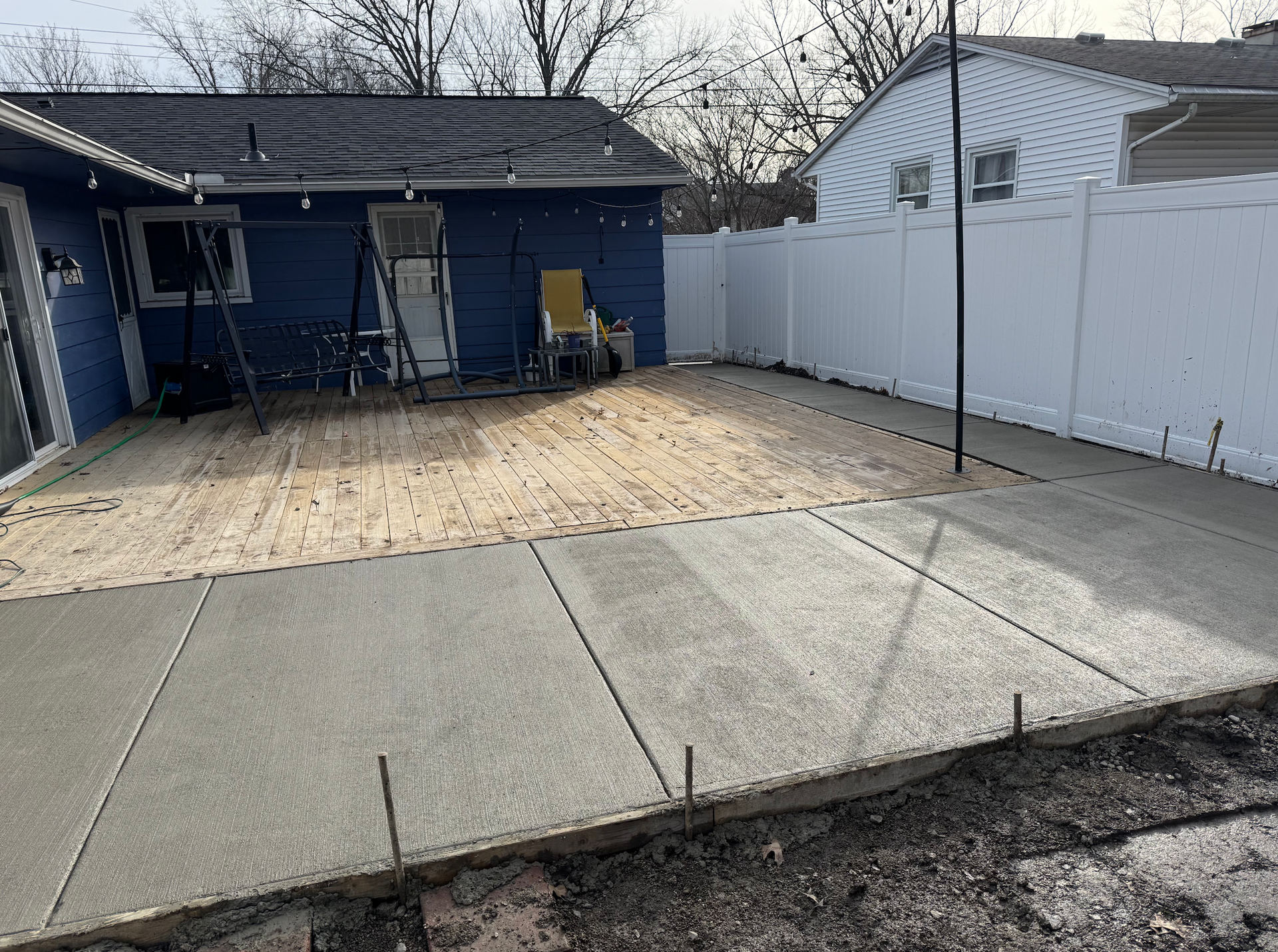 A concrete patio is being built in the backyard of a house.