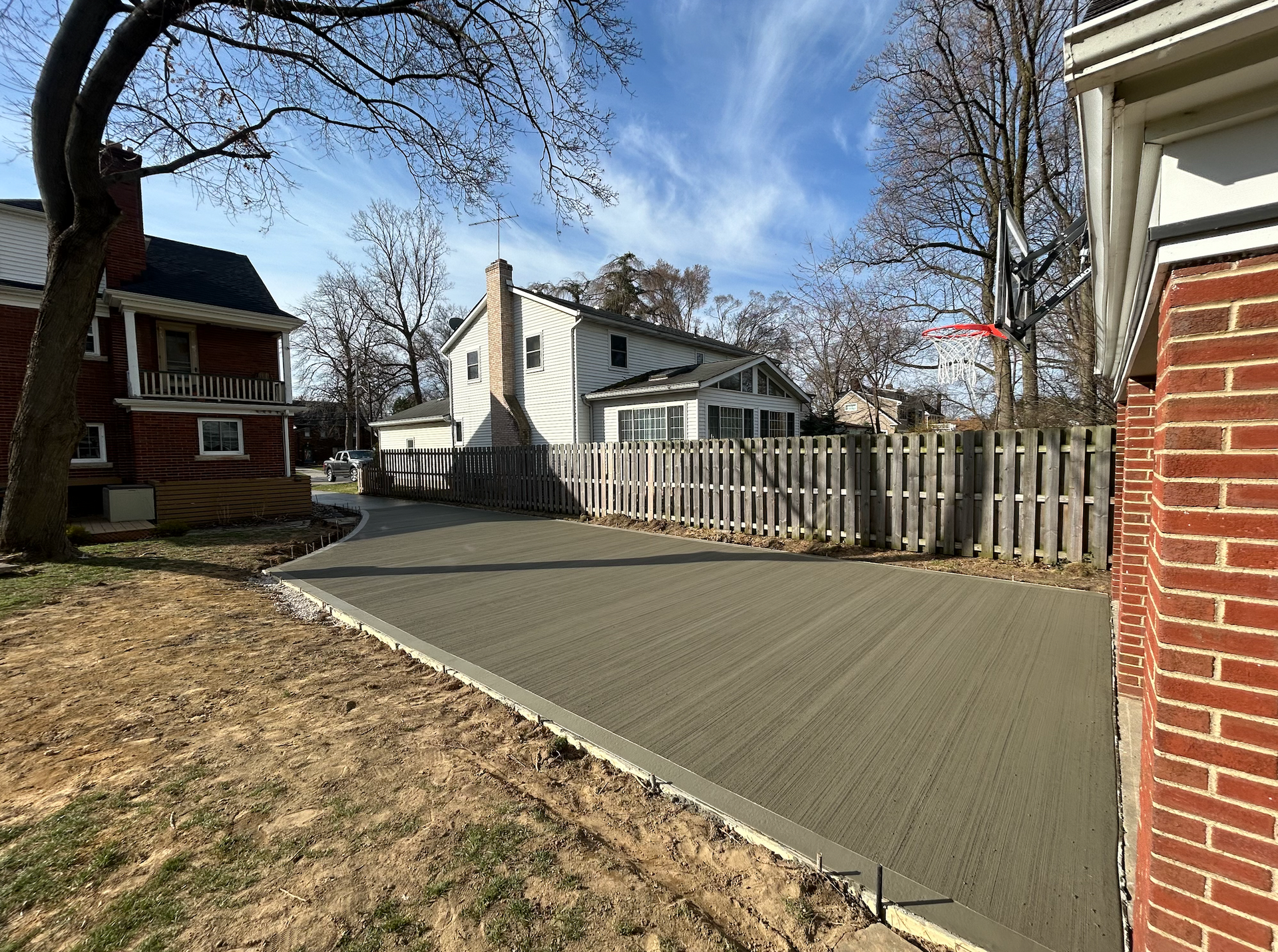 A concrete driveway is being built in front of a brick house.