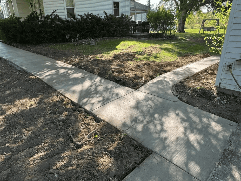 A concrete sidewalk is being built in front of a house.