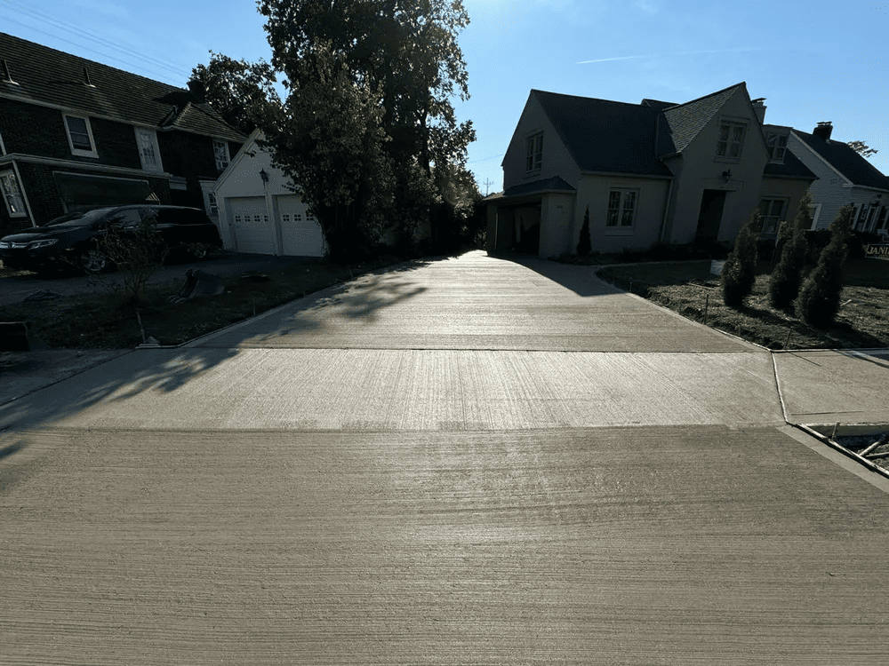 A concrete driveway leading to a house in a residential neighborhood