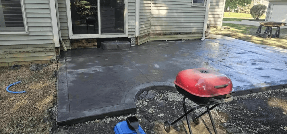 A red grill is sitting on a concrete patio in front of a house.