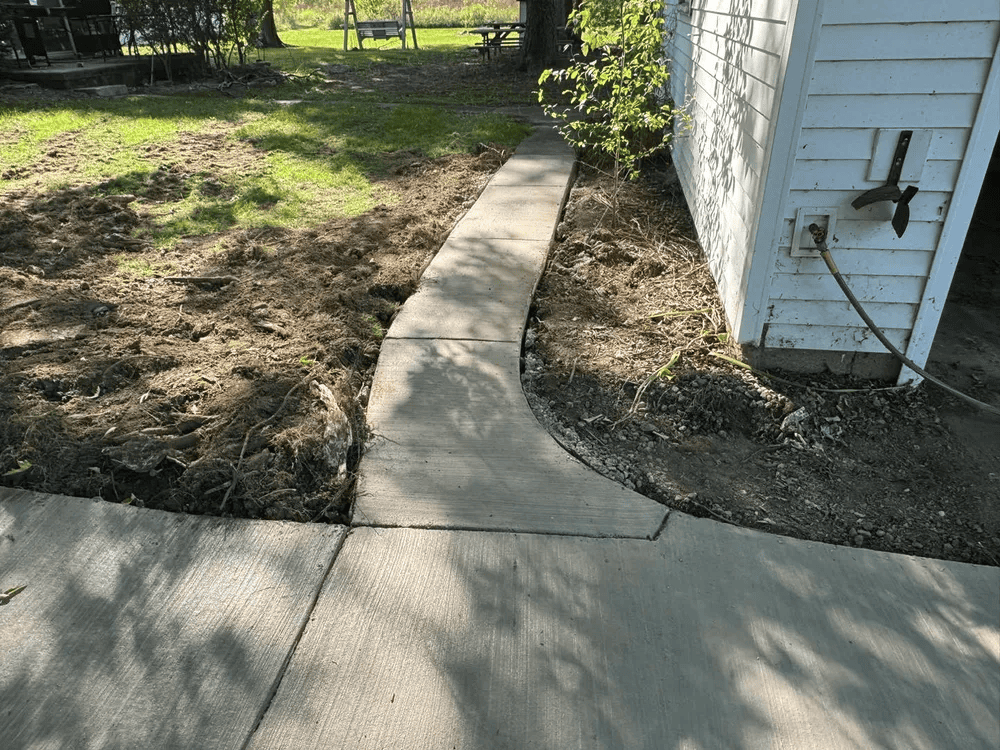 A concrete walkway leading to a garage next to a house.
