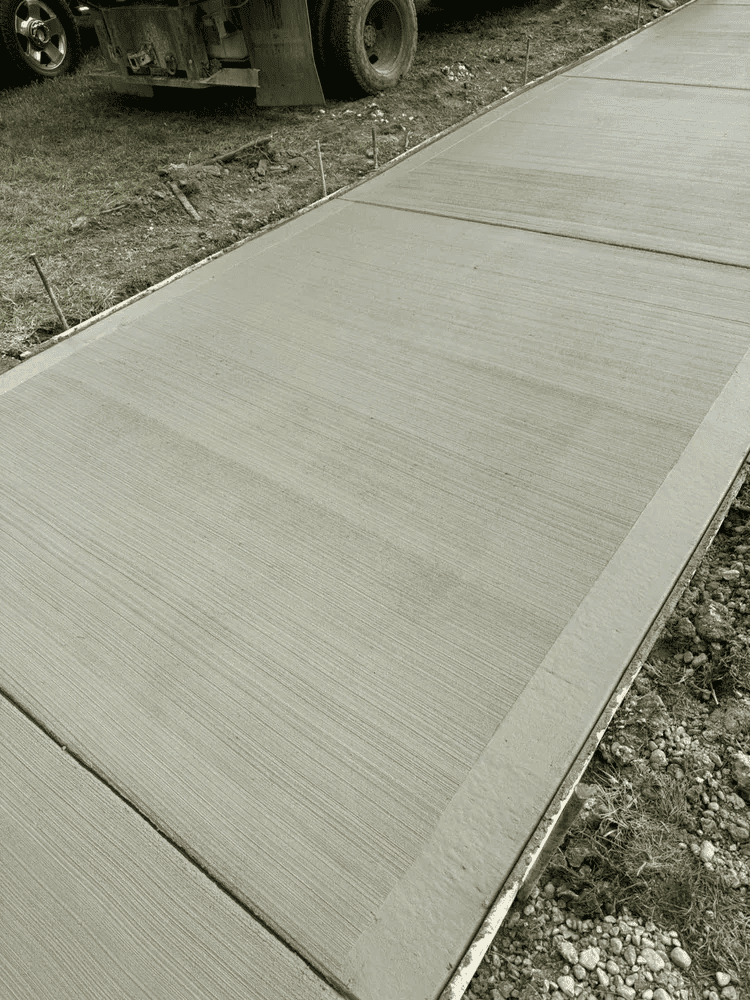A black and white photo of a concrete sidewalk with a truck in the background.