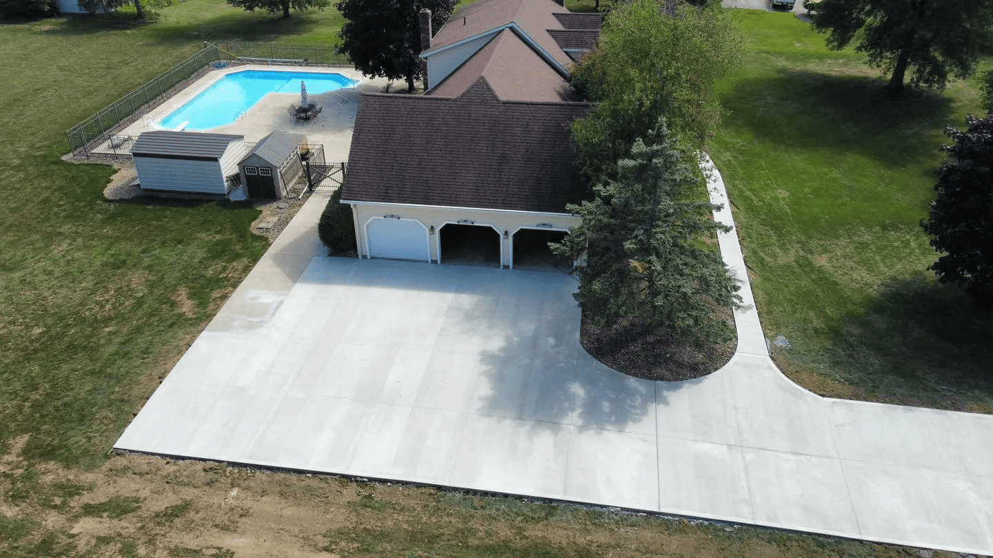 An aerial view of a house with a driveway and a pool.