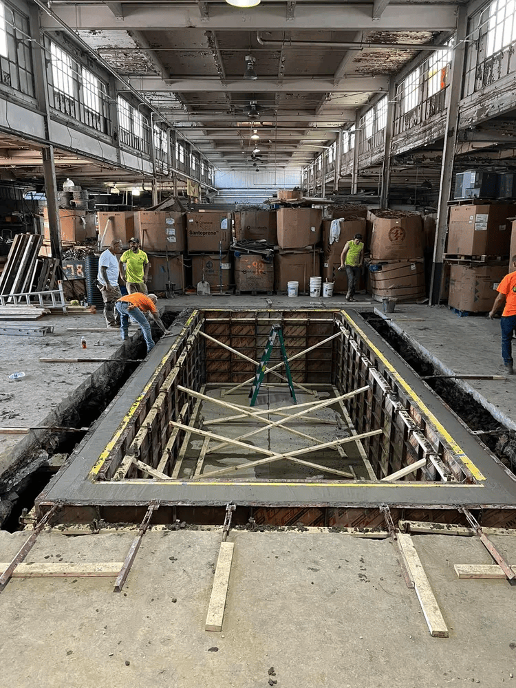A large concrete pool is being built in a large building.
