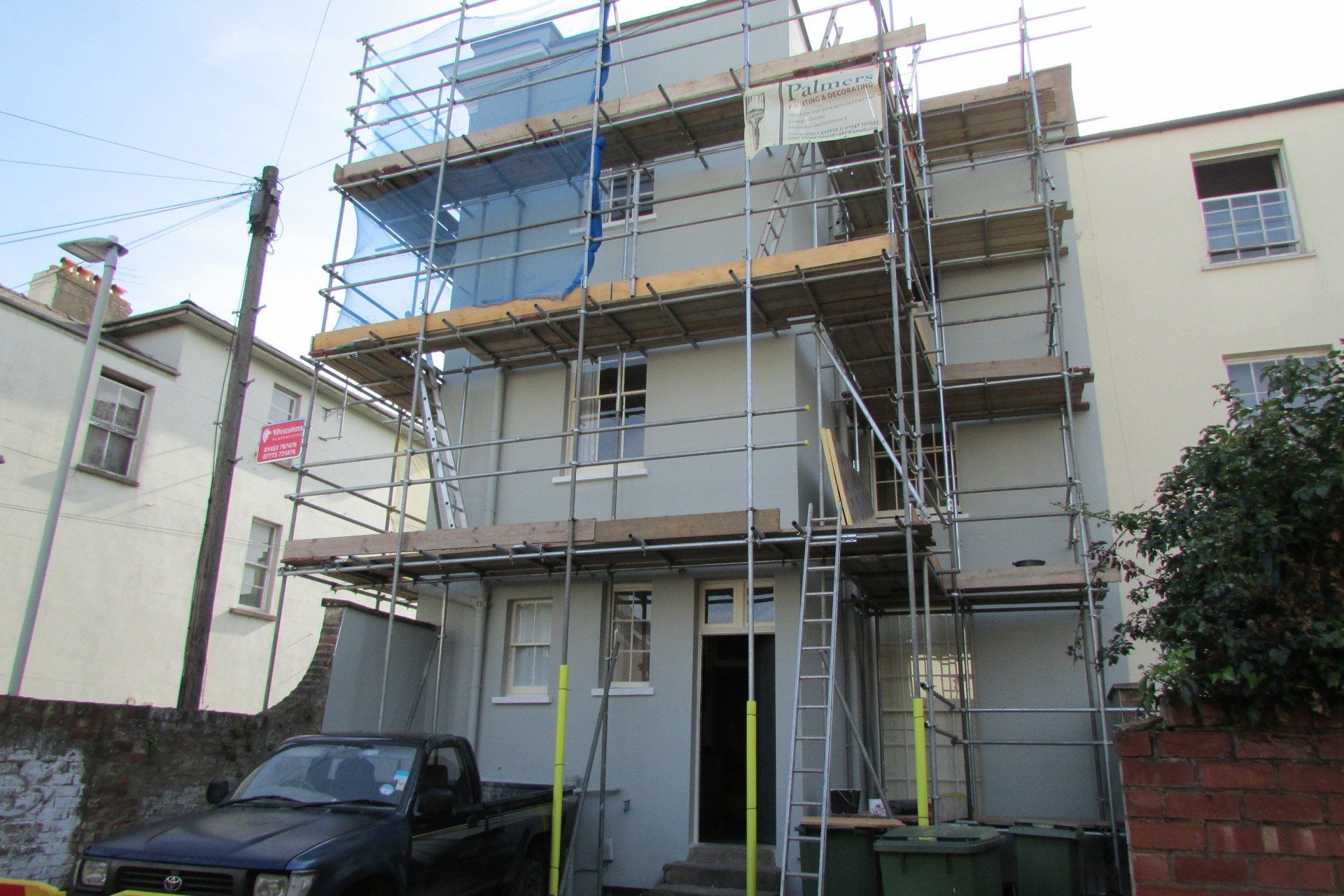 A truck is parked in front of a building with scaffolding on it.