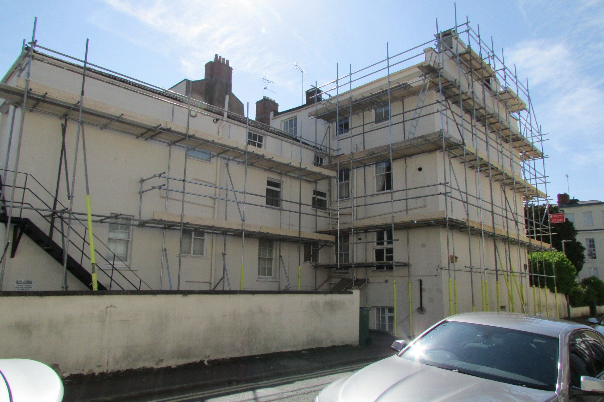 A large building with scaffolding around it and a car parked in front of it.